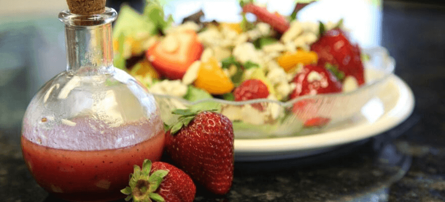 Bottle of strawberry vinaigrette in front of a strawberry salad