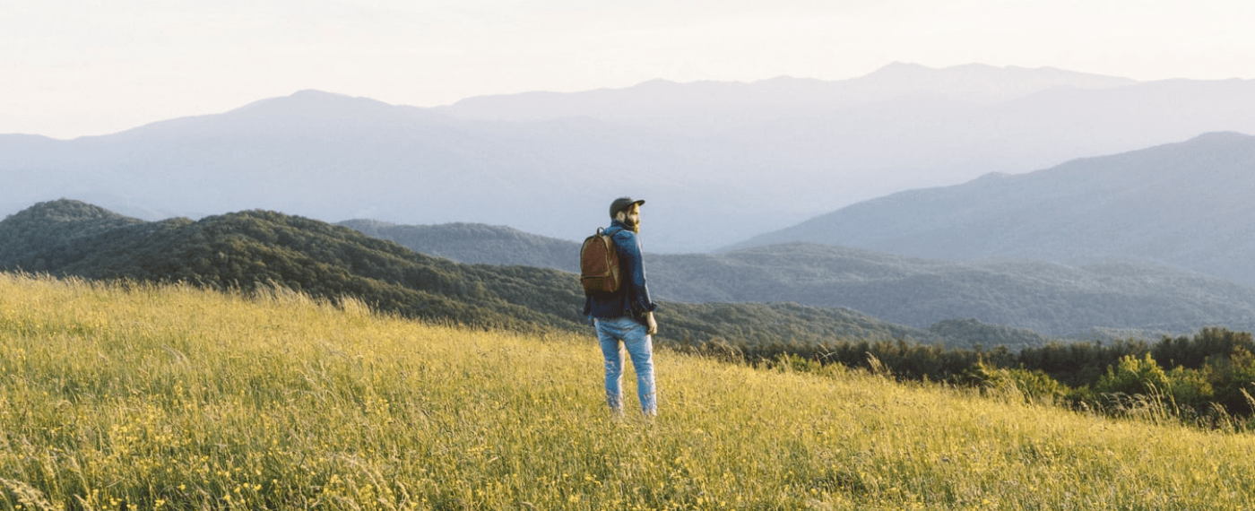 Man standing in field looking into the distance thinking about living a happy life