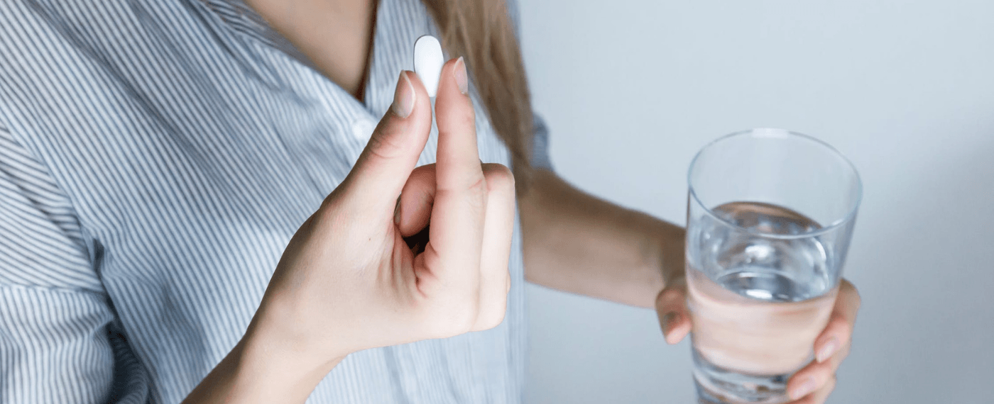 woman with a glass of water taking a probiotic for gut health