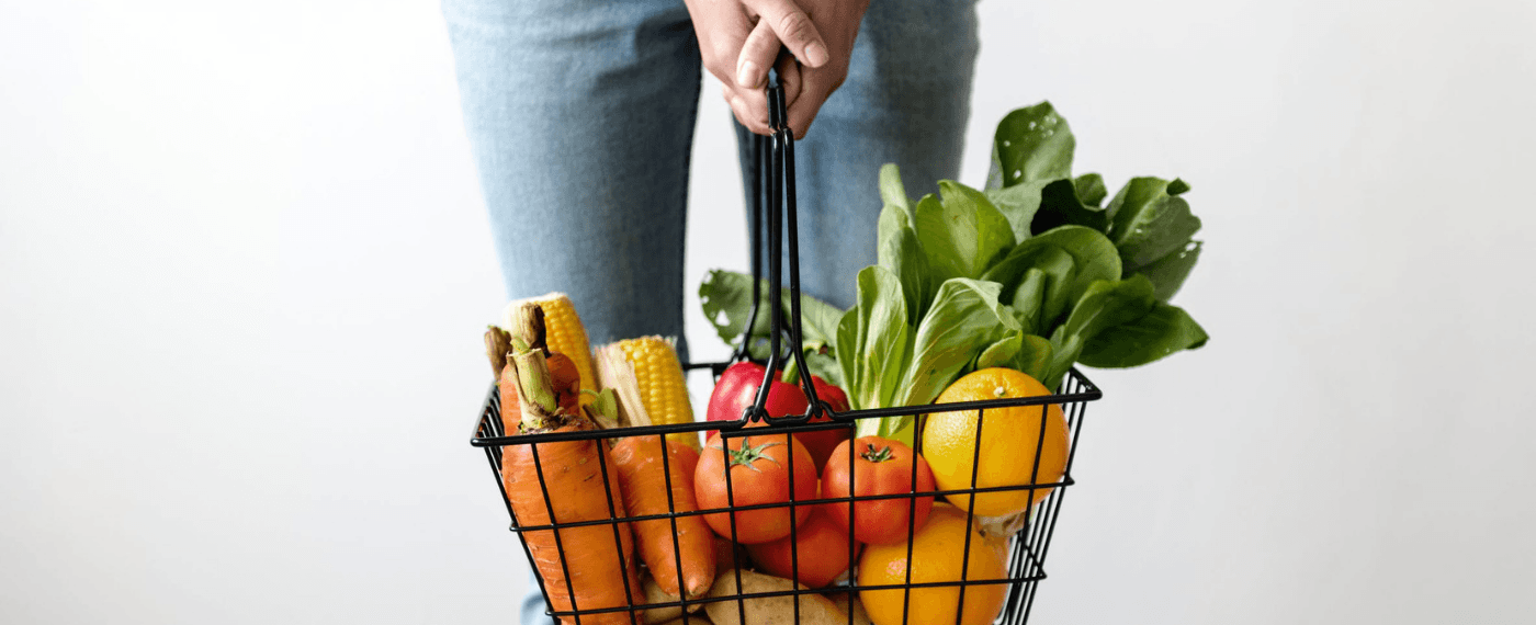 woman holding grocery basket full of fresh vegetables