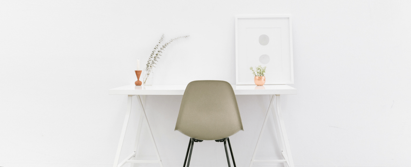 A minimalist white room with desk and chair