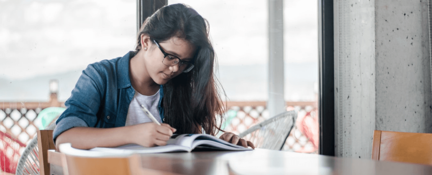 girl sitting at tbale writing in journal about improving yourself