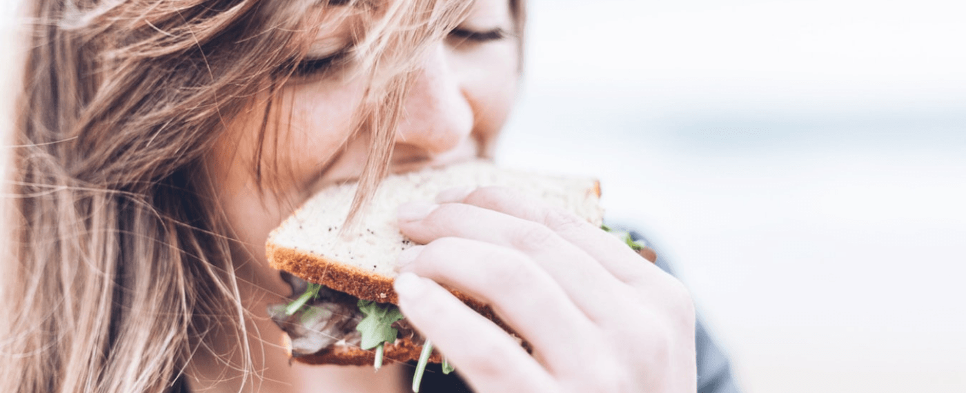 A woman enjoys biting into a sandwich