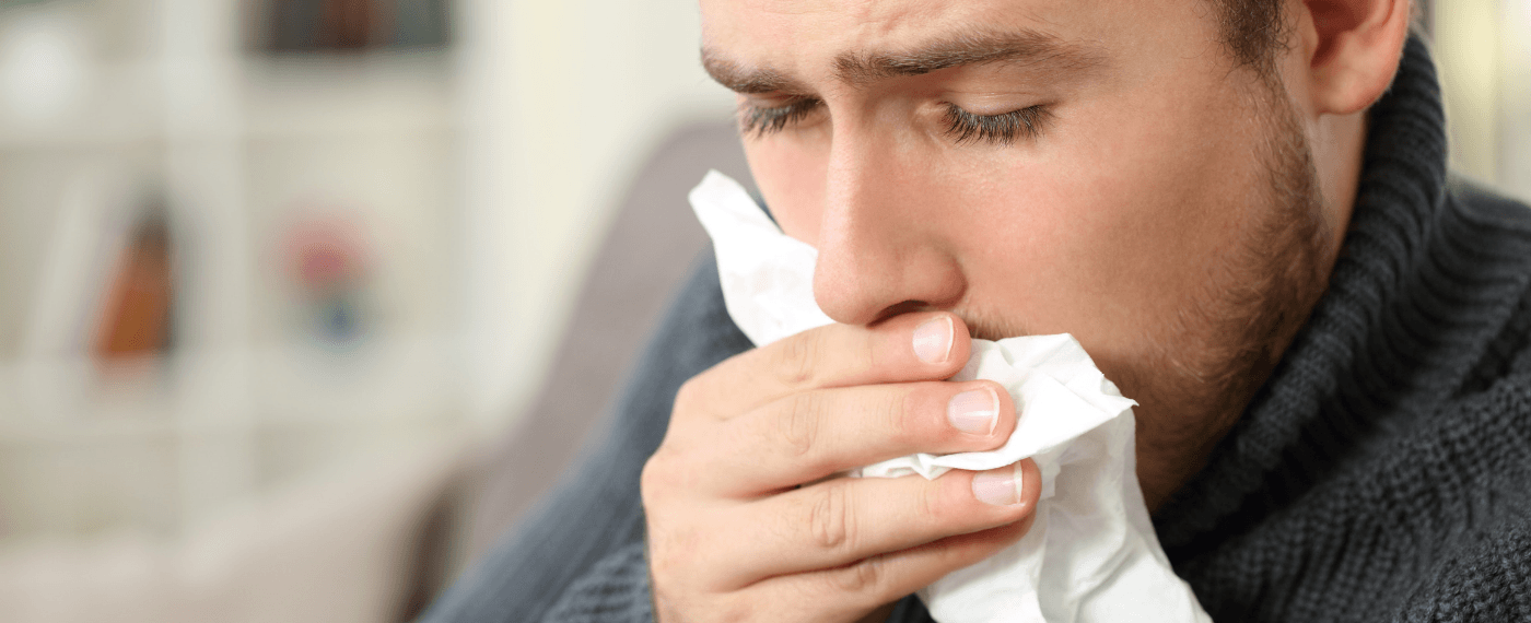 Man holding tissue to mouth to cover cough