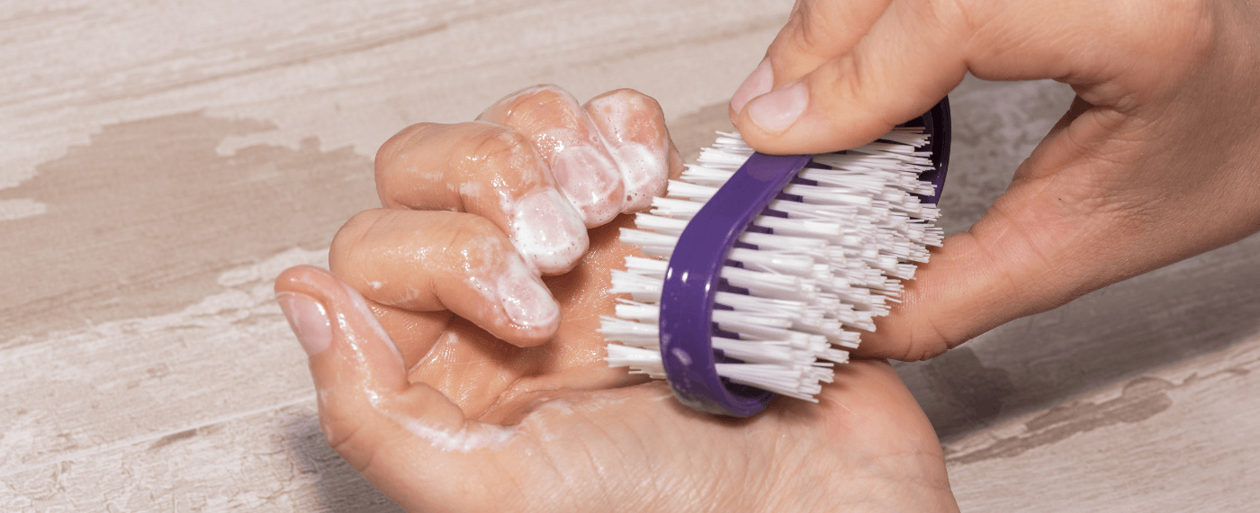 Woman scrubbing nails with a bristle brush