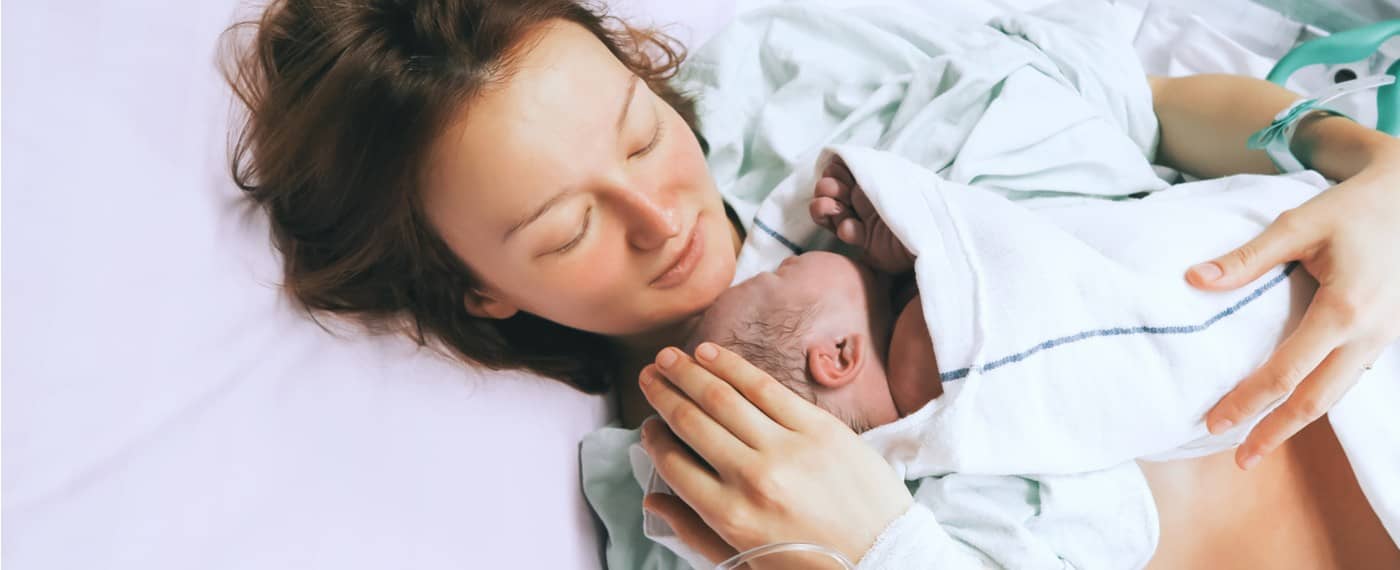 A new mother holds her newborn baby in a hospital bed