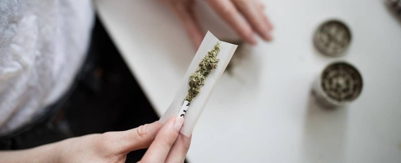 A woman rolling up cannabis intoa joint