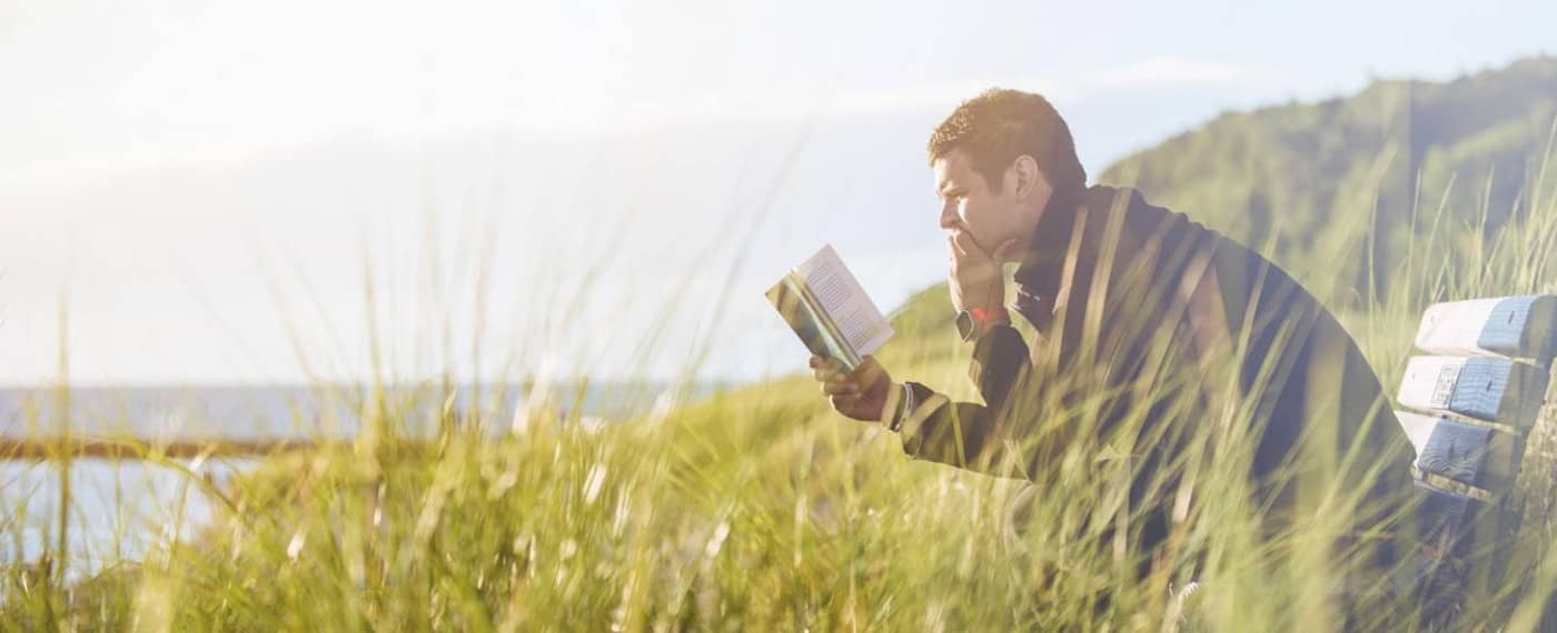 man reading a book in a field about making time for intimacy