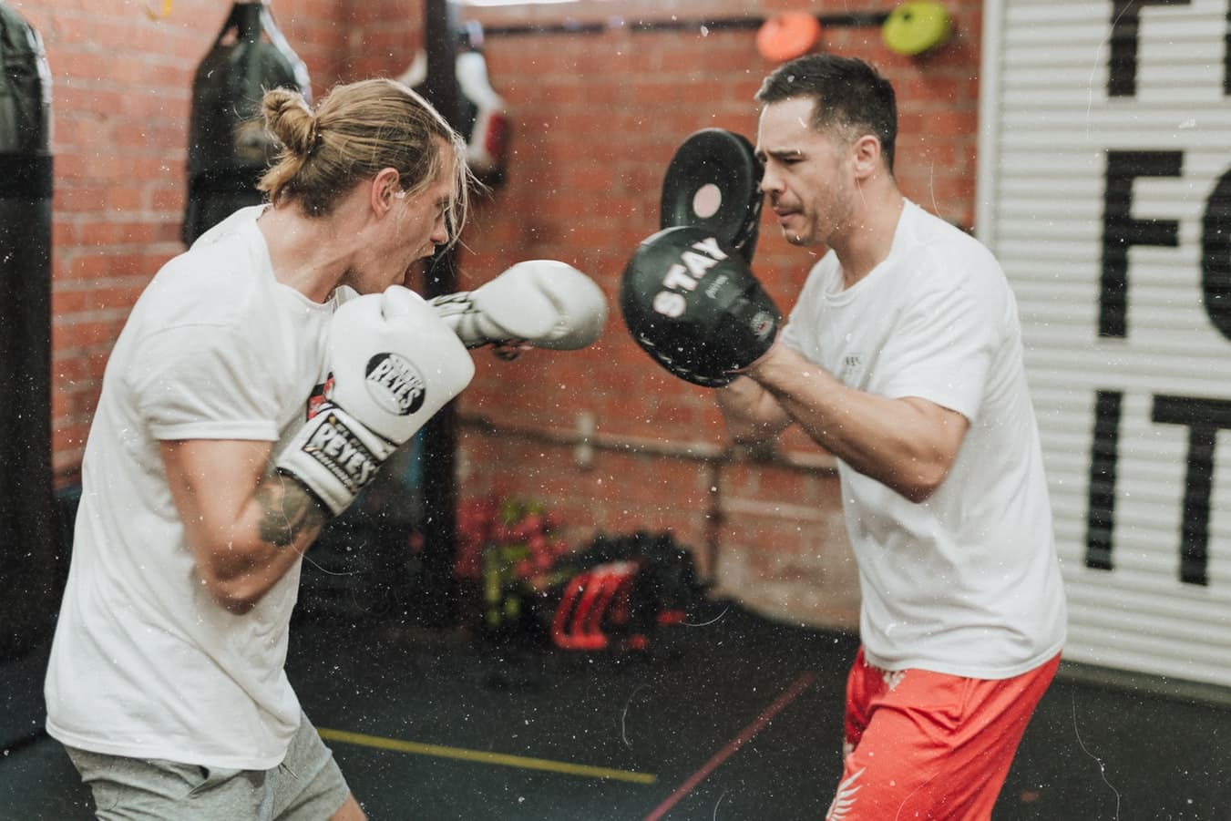 male boxing trainer helping male boxer practice