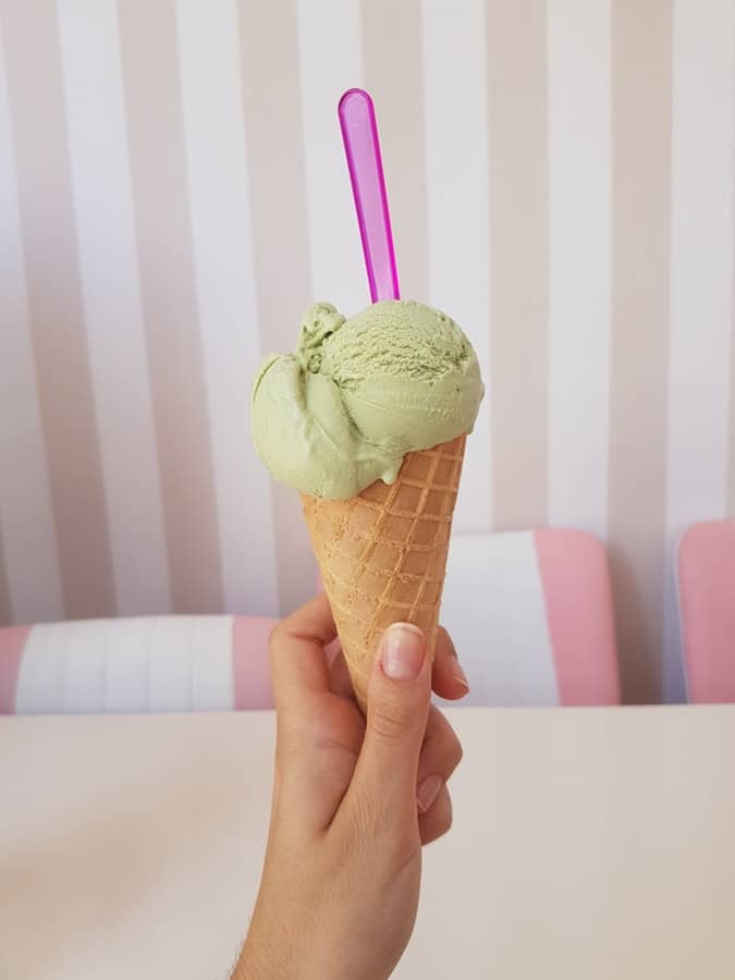 Girl's hand holding an ice cream cone with cbd ice cream on top