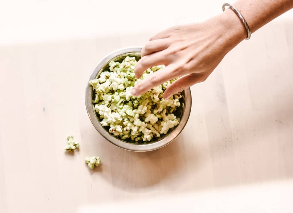 A hand reaching for a bowl cbd popcorn