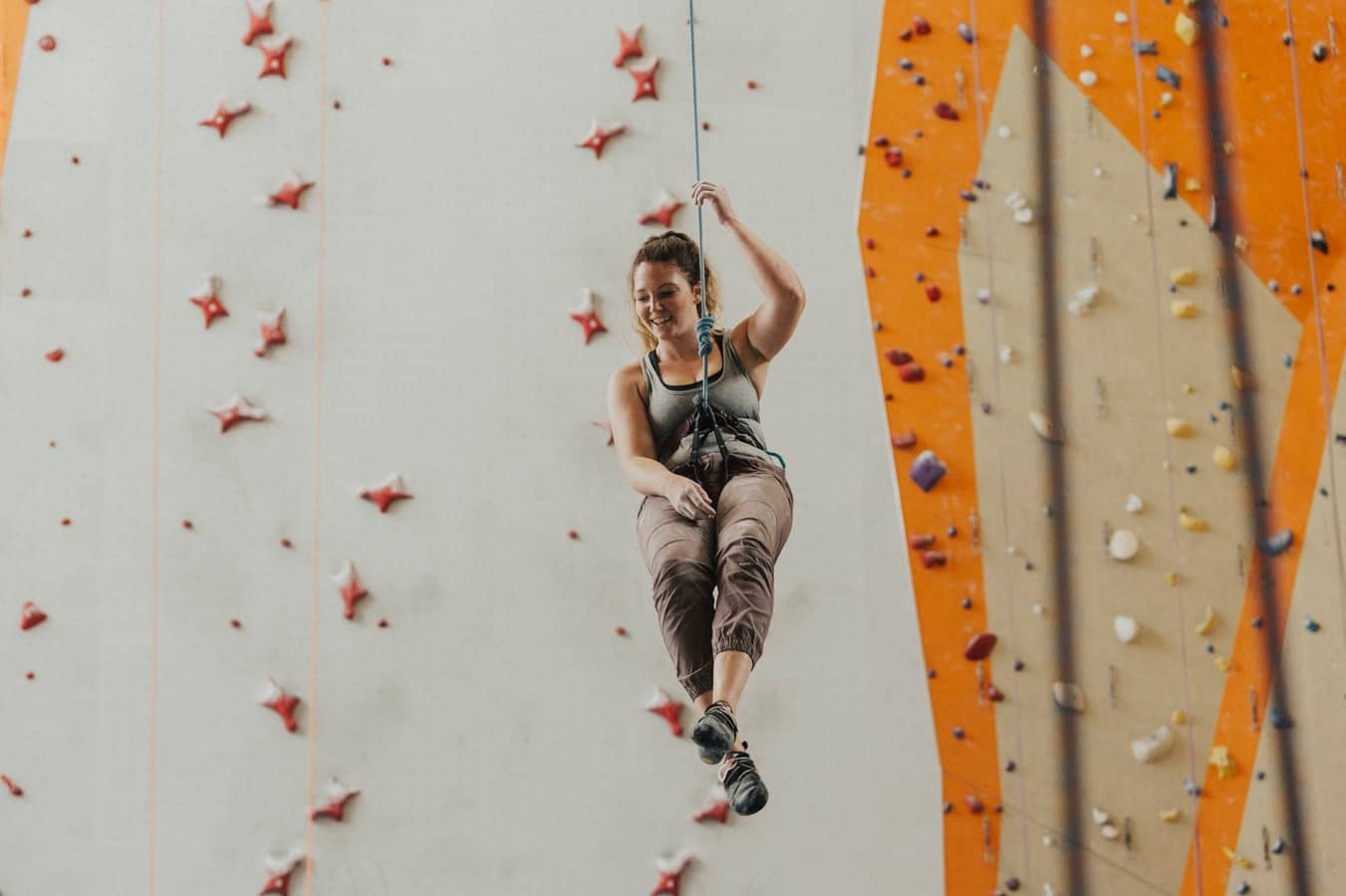 woman rappelling down a rope during indoor rock climbing