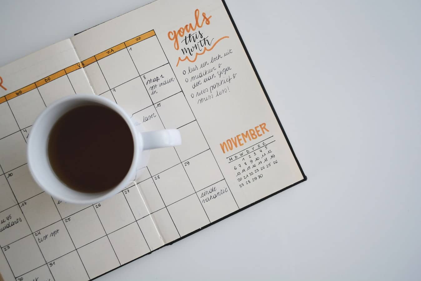 Cup of coffee sitting on top of an empty monthly goal planner