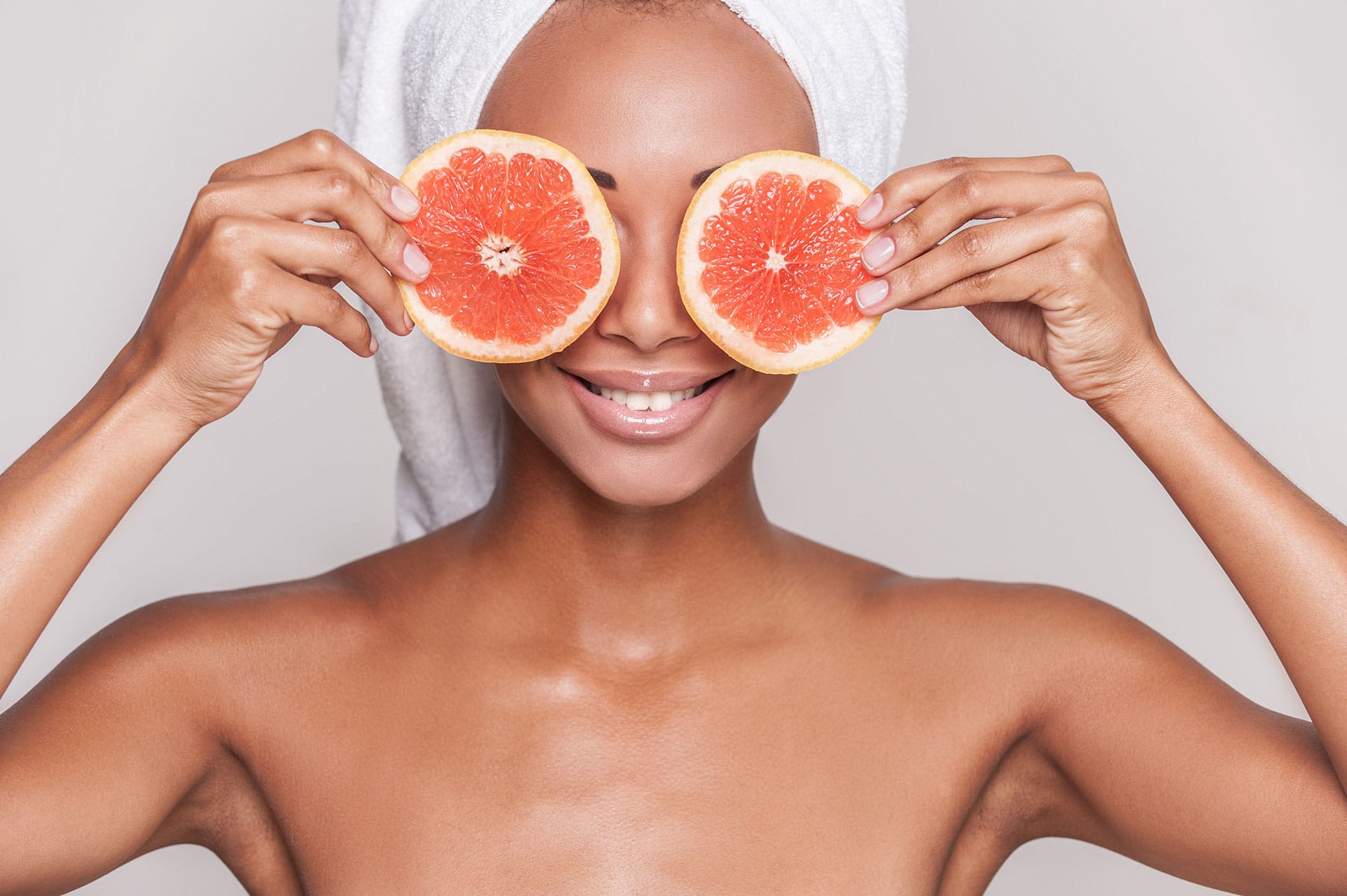 Woman holding grapefruit slices in front of her eyes