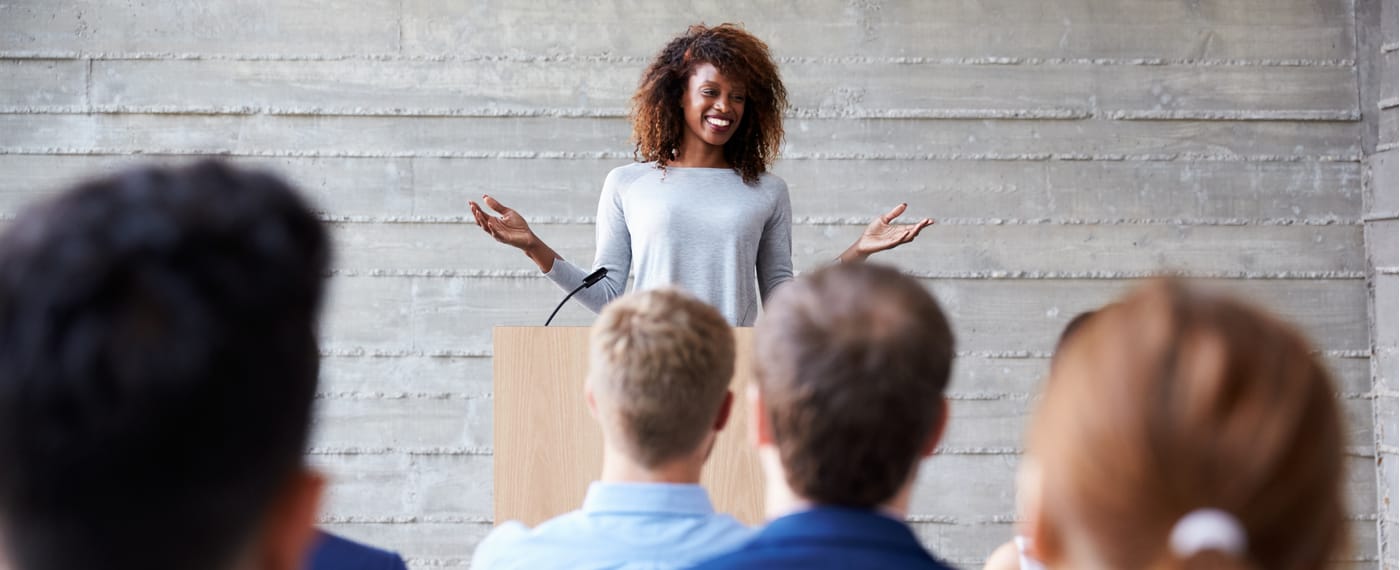 Female motivational speaker smiling in front of a group of listeners