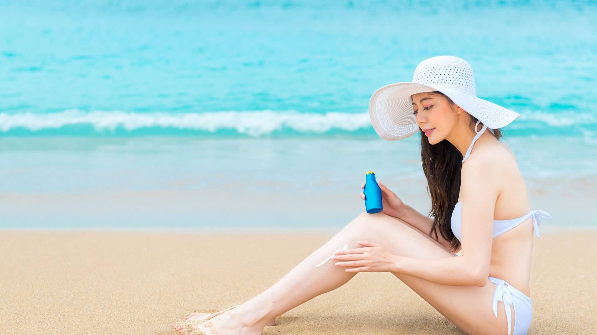 Lady on the beach applying korean sunscreen to her leg