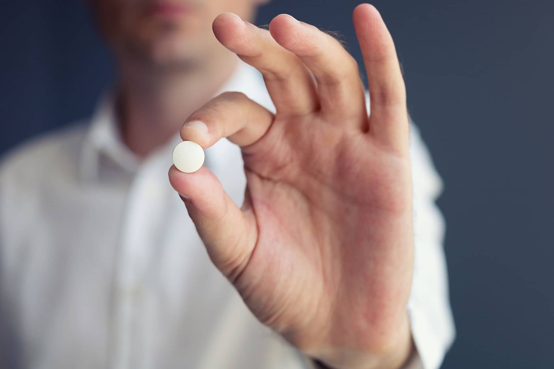man holding the miracle drug aspirin pill