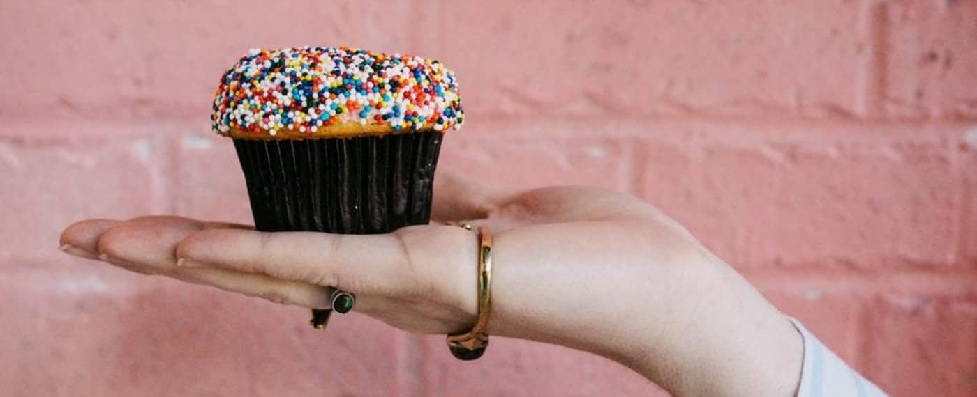a hand holding a sprinkle cupcake infused with cbd
