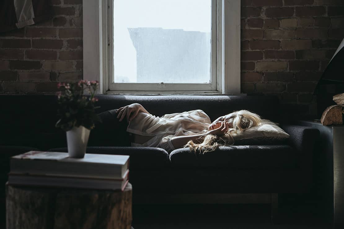 Woman taking a nap on couch next to the window