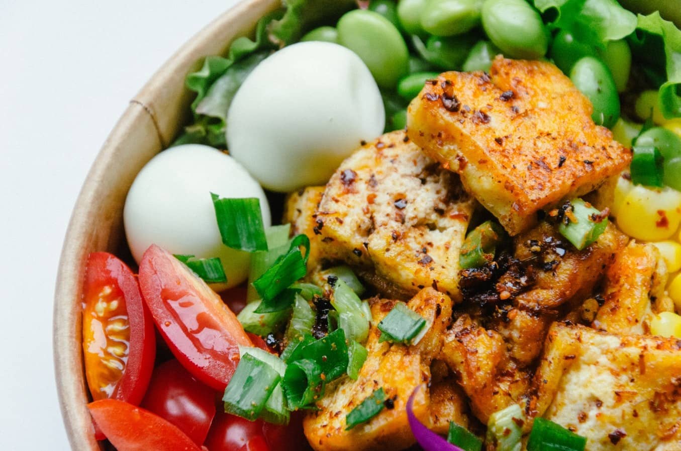 A bowl of tofu with vegetables and hard boiled eggs