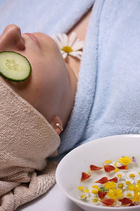 woman receiving spa treatment with cucumber slices over her eyes