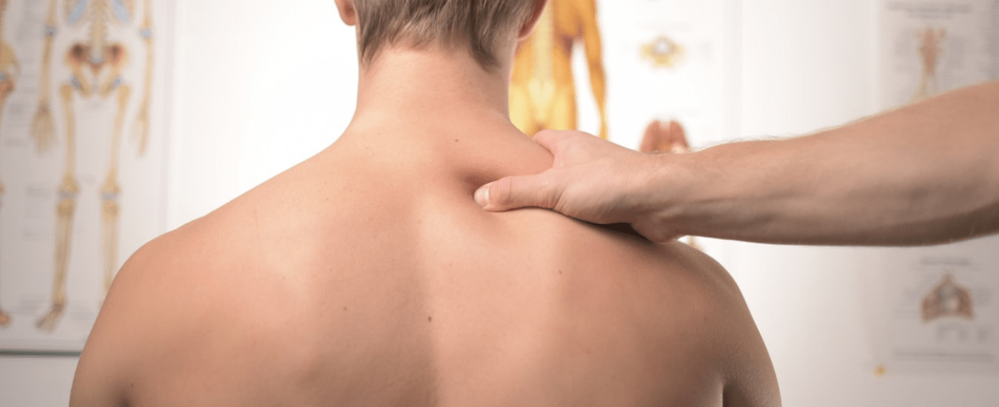 Shirtless male in doctors office getting his shoulder checked out by physician