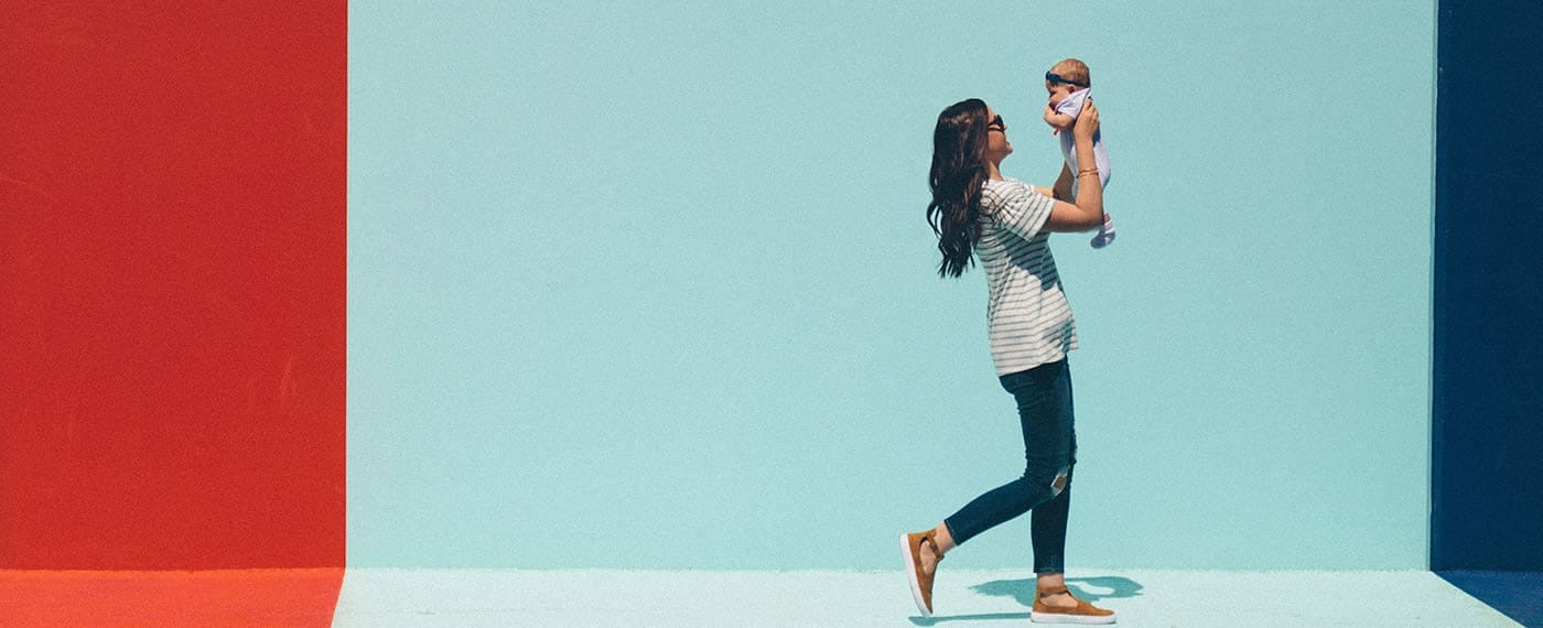 Woman walking while holding and looking up at newborn baby