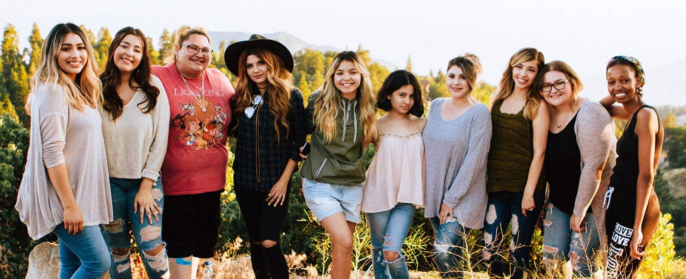 A group of women of different sizes, races, and styles smiling together