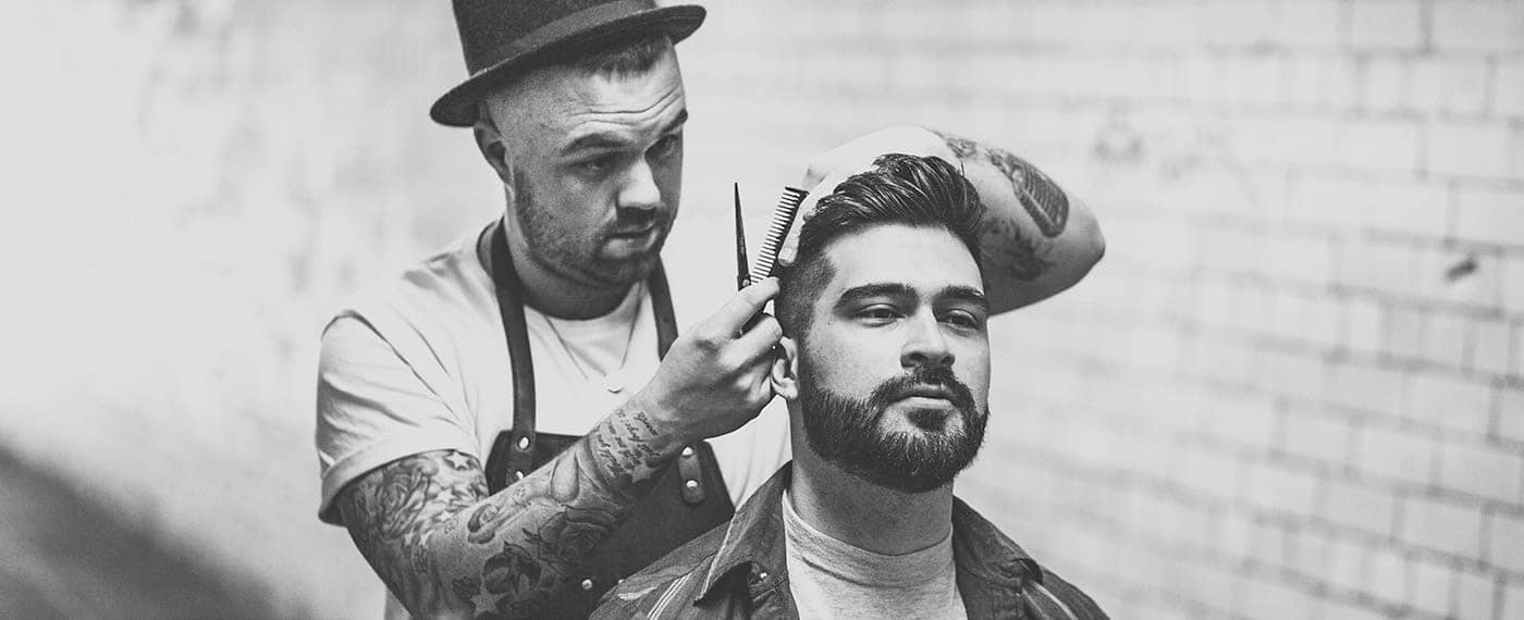 Barber with scissors and comb grooming a man's hair