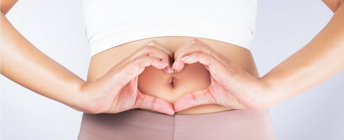 Woman making the shape of a heart with her hands over her belly button