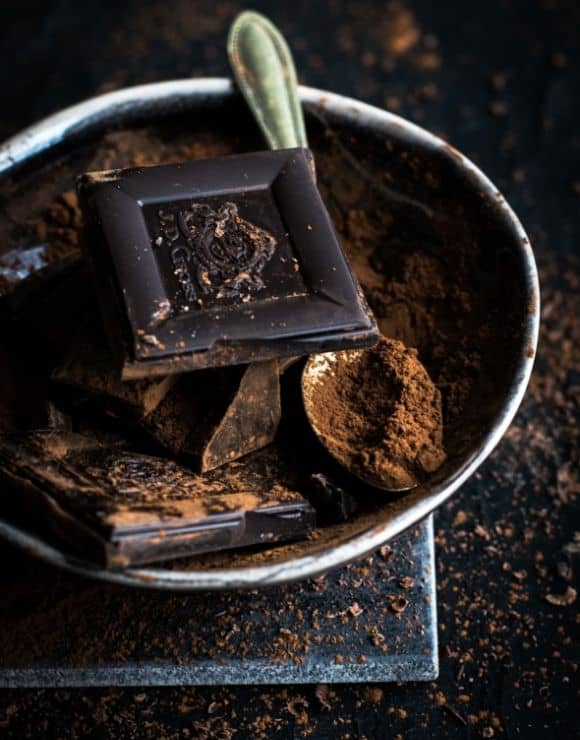 a bowl of dark chocolate pieces and powder rich in antioxidants
