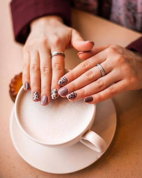 woman showing off trendy manicured nails over coffee mug