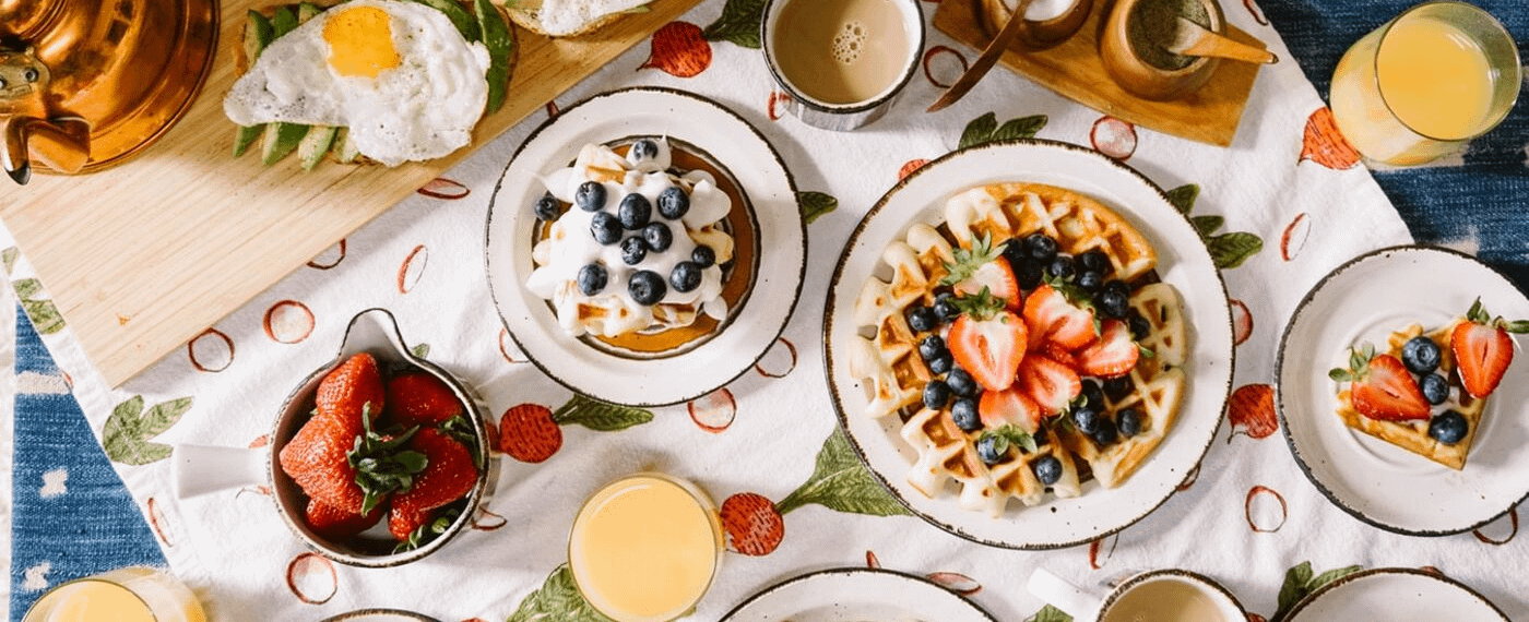 Variety of brunch dishes including waffles, pancakes, strawberries, and juice