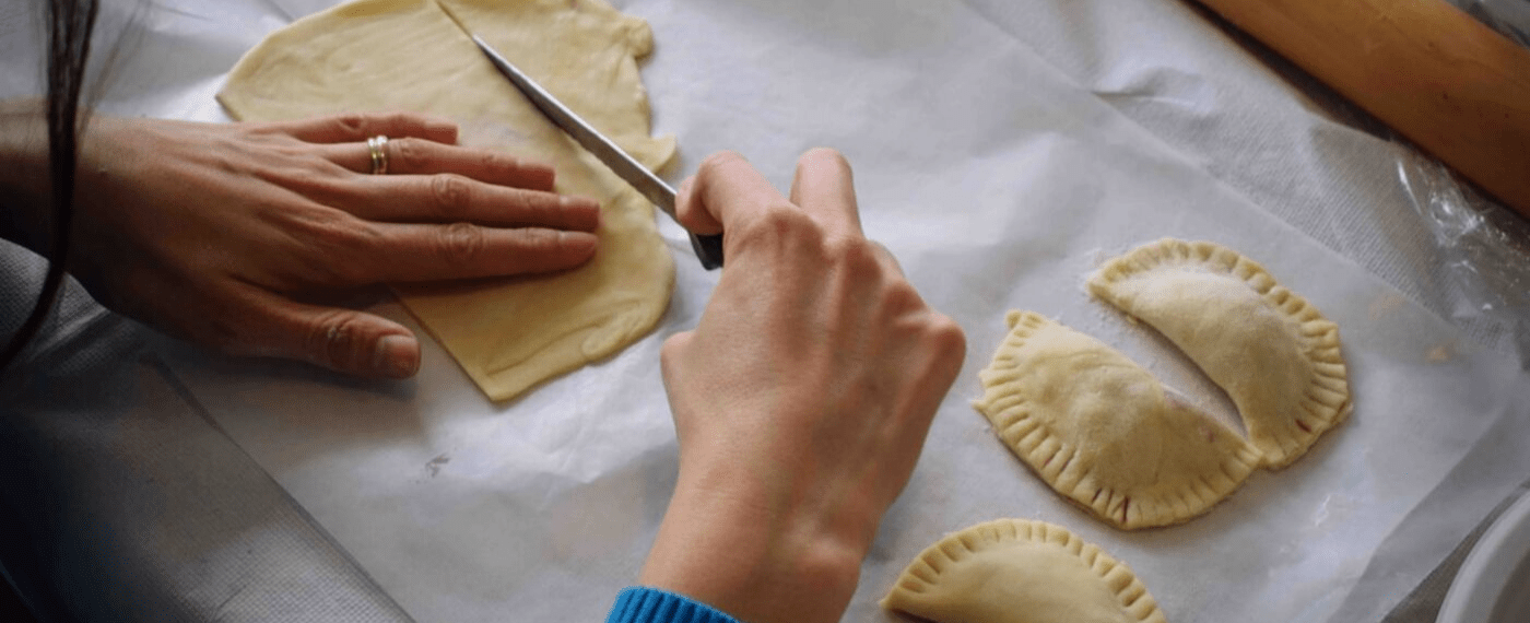woman carefully slicing dough with a sharp knife to make pastries