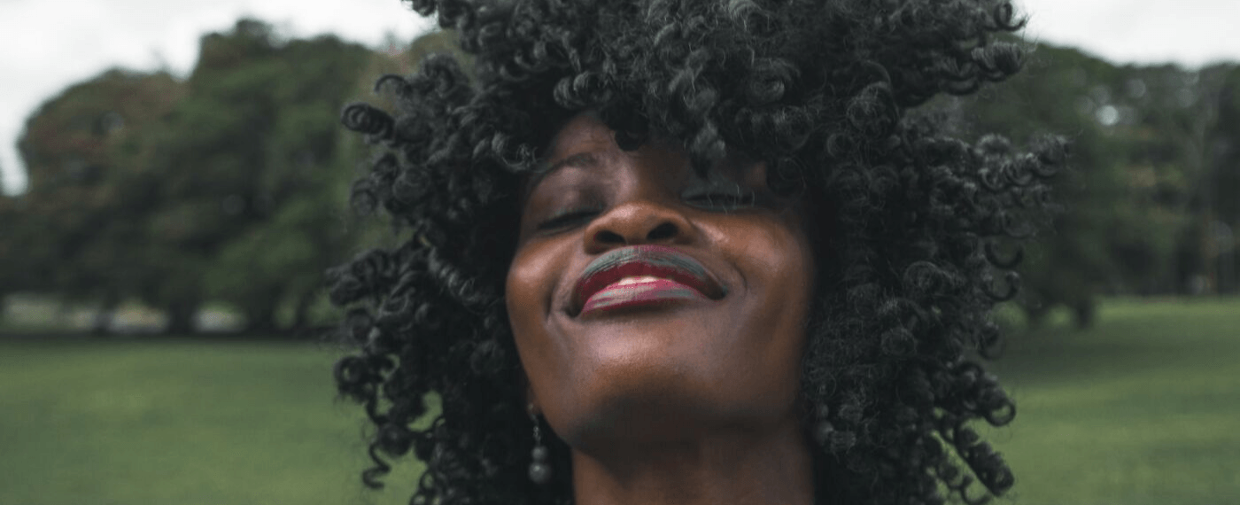 woman smiling with her eyes closed saying positive phrases to herself