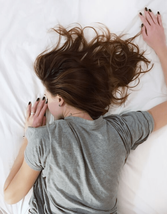 Woman lying restless in bed on her stomach due to unhealthy intermittent fasting