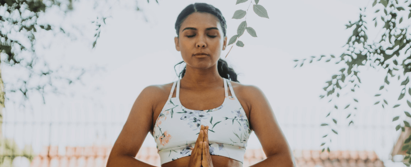 Woman meditating with hands folded against her chest