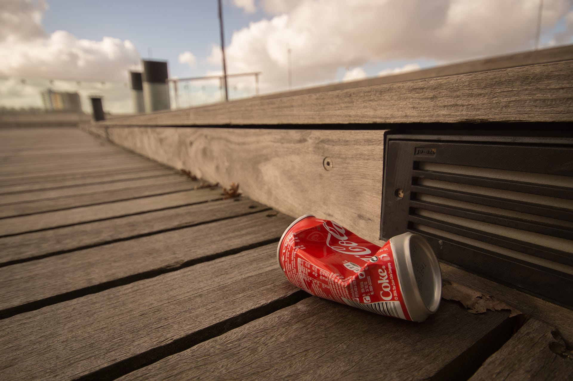 A single crushed can of coco-cola littered on the sidewalk