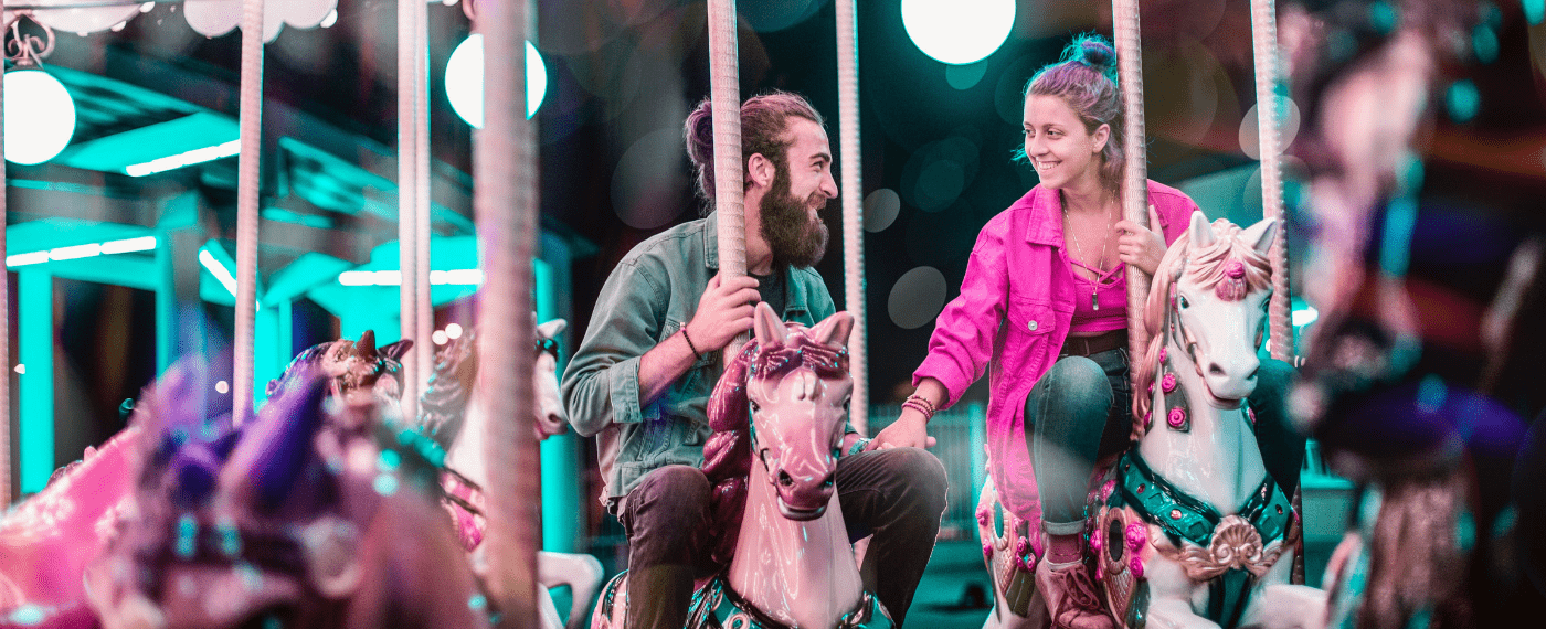 man and woman riding a merry-go-round while holding hands
