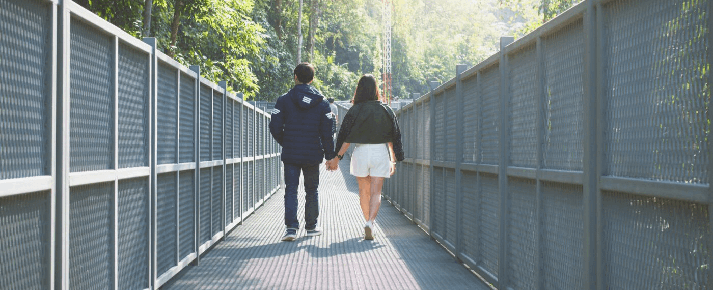Couple walking hand in hand across a metal bridge