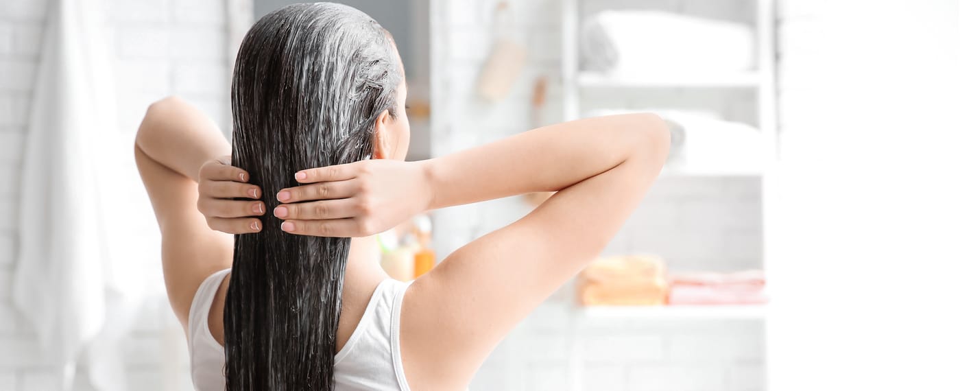 woman gently applying conditioner to her hair