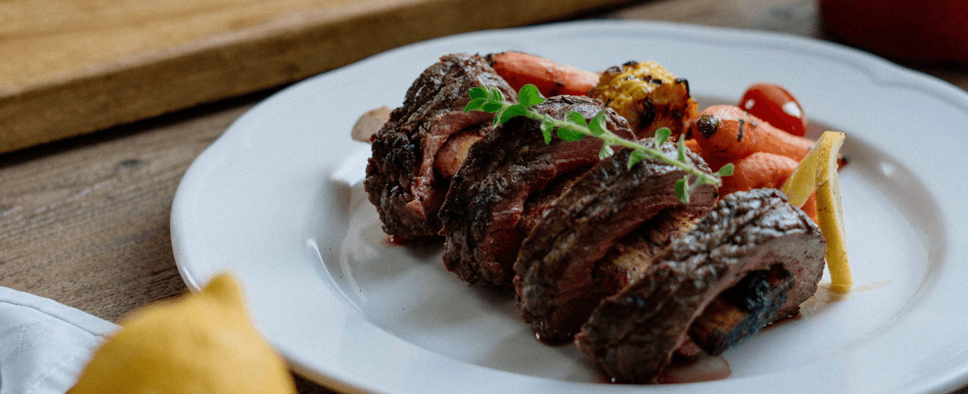 A plate of grilled steak on the bone with carrots on the side