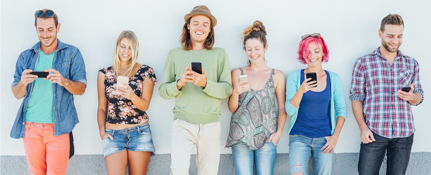 Group of friends smiling and looking down at their phones on Instagram