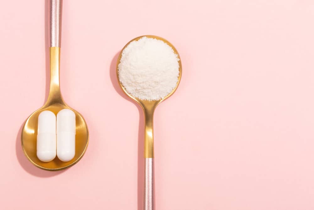 A spoon of capsules next to a spoon of makeup powder
