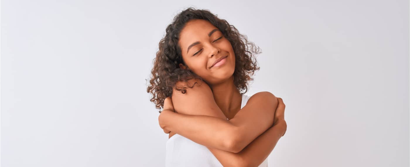 Woman smiling while giving herself a hug