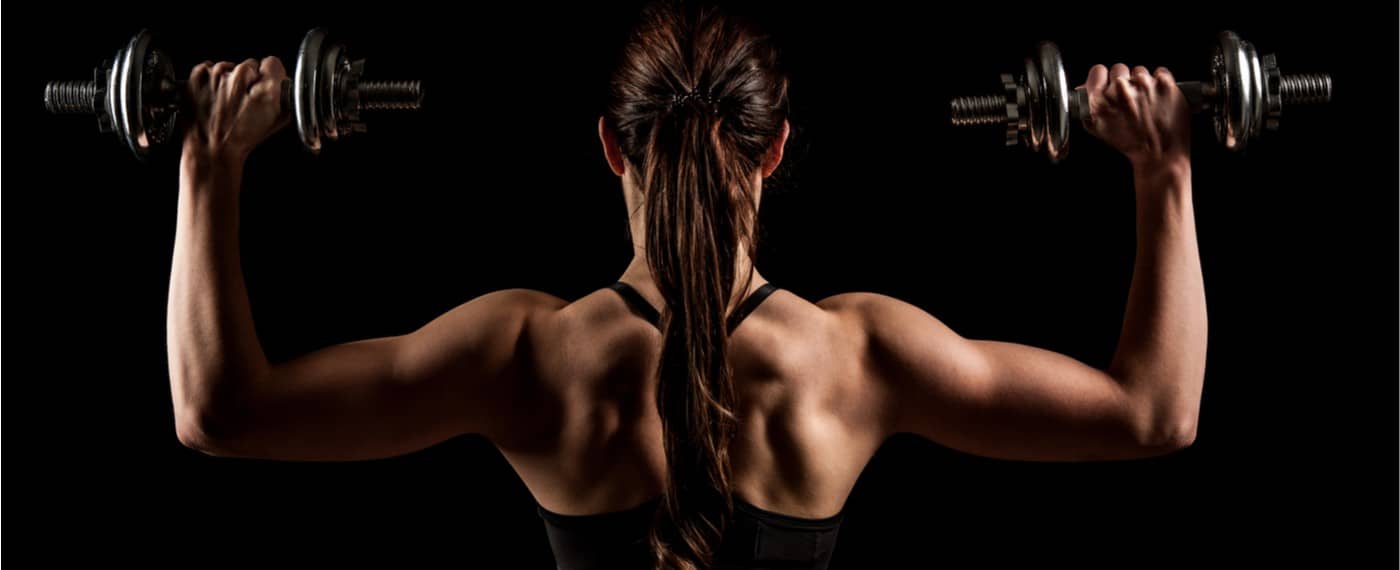 Athletic female showing off back muscles holding two dumbbells