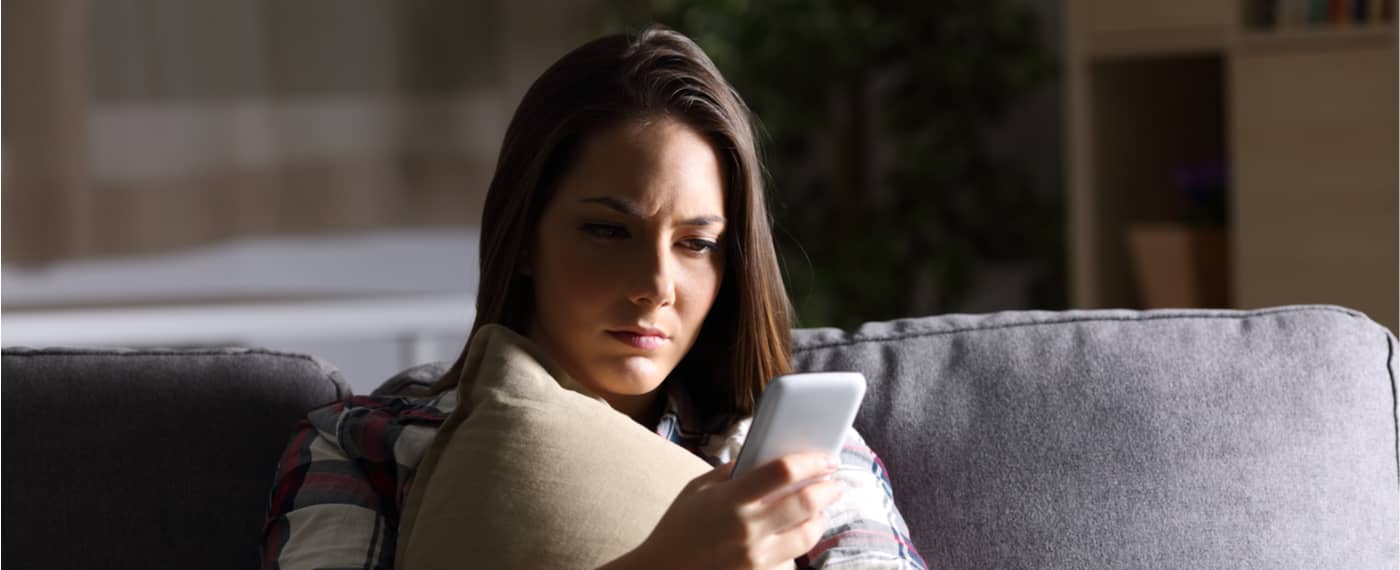 Woman looking upset at phone after being ghosted by friends