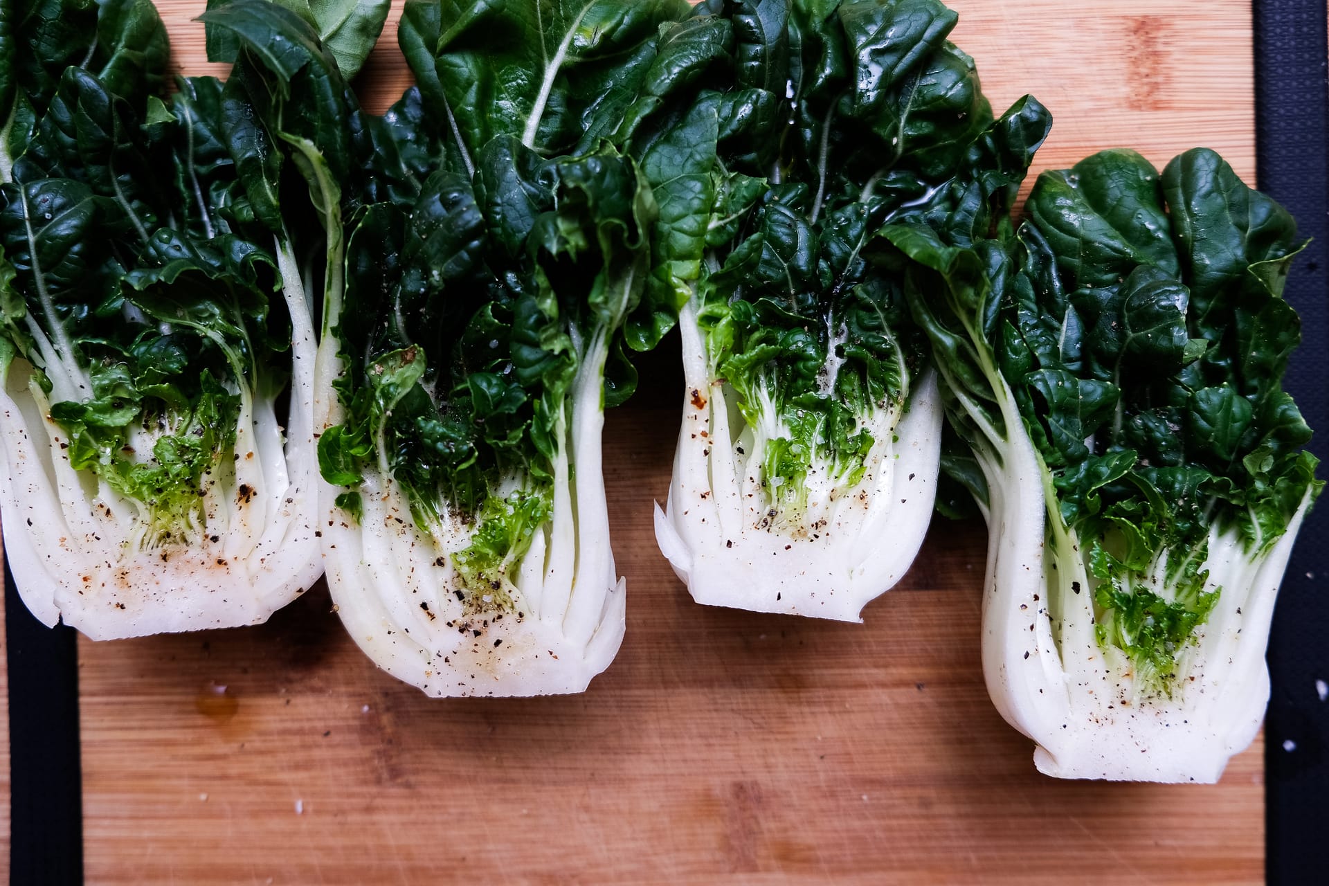 Four pieces of Bok Choy on a wooden cutting board