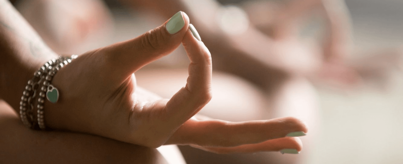 A woman with stylish nails meditates in a yoga pose