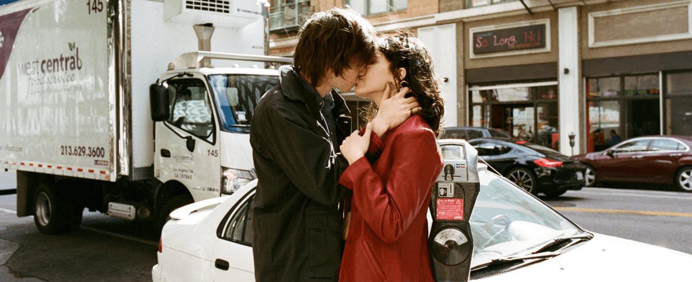 Young couple kissing in front of a street parking meter
